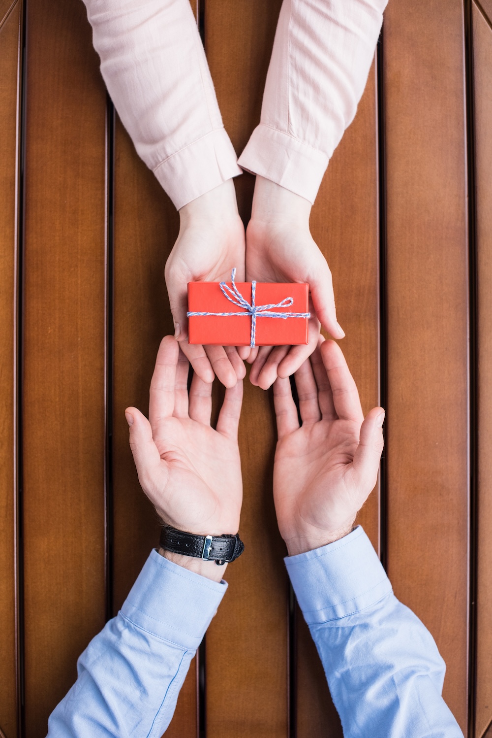 cropped image of girlfriend gifting present box to boyfriend